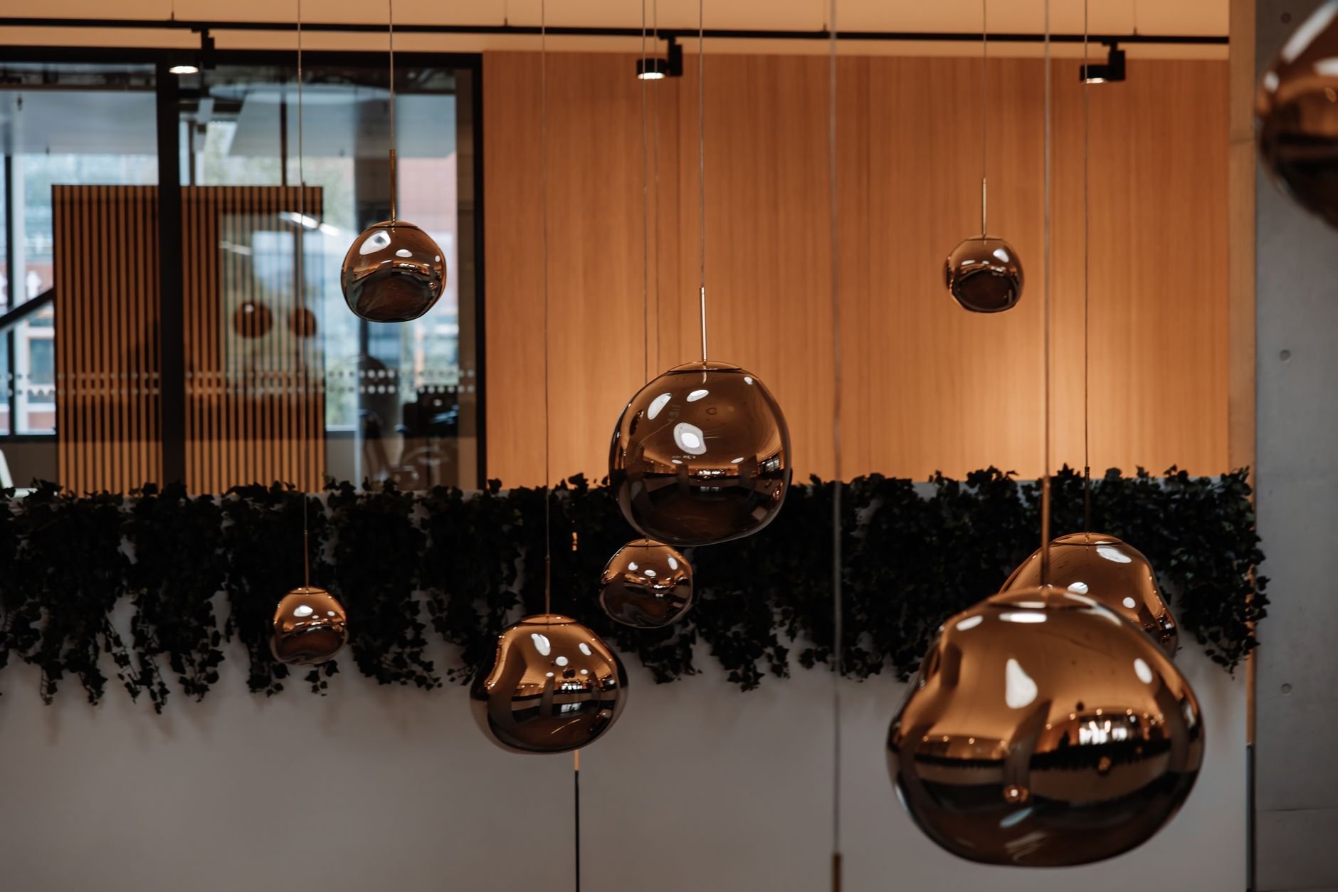 Warm and stylish modern office interior with reflective hanging spheres and natural decor.